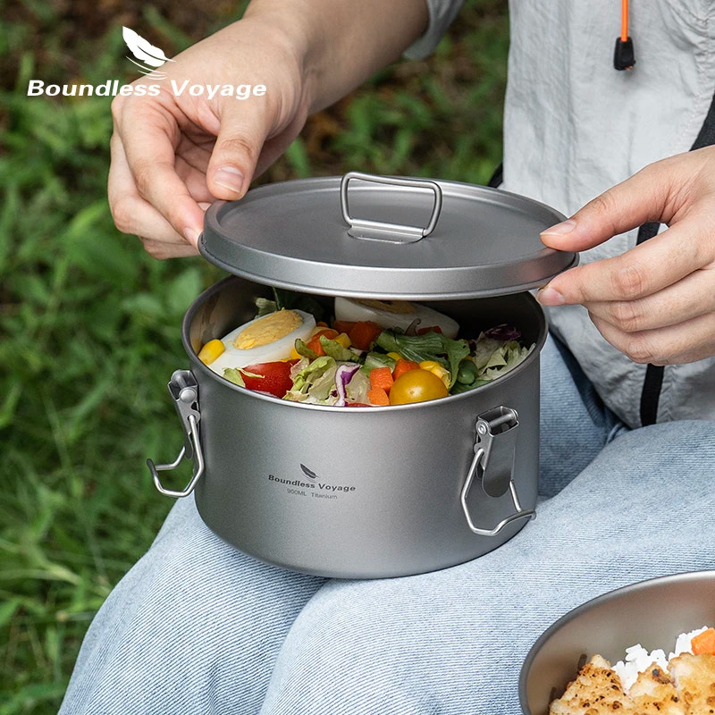 Person opening a portable cooking pot filled with food outdoors, with 'Boundless Voyage' branding.