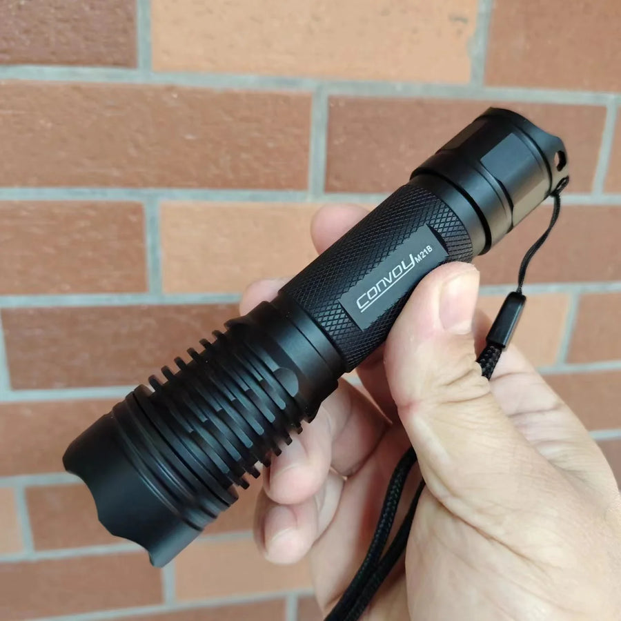 Black flashlight held in a hand with a brick wall background