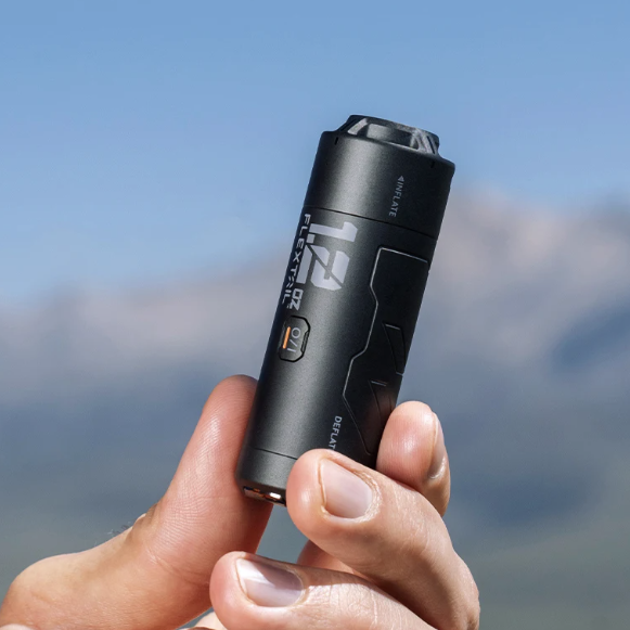Person holding a black air pump with a blurred mountain background