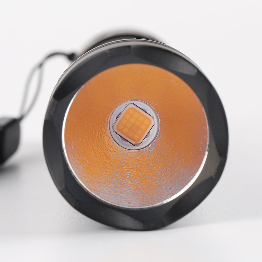 Close-up of a round flashlight with orange lens and black casing on a white background