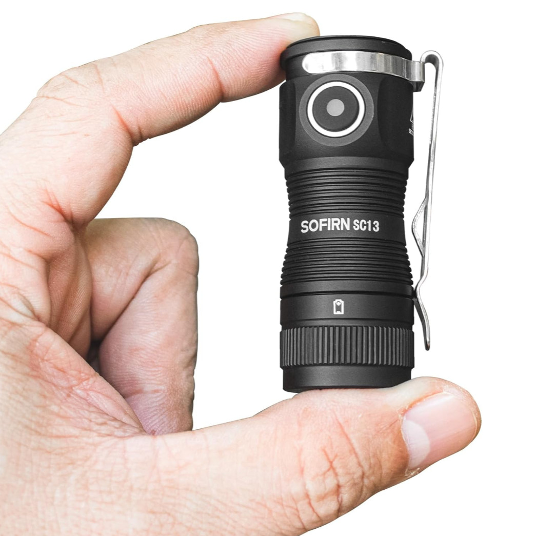 Black flashlight held in a hand with a white background