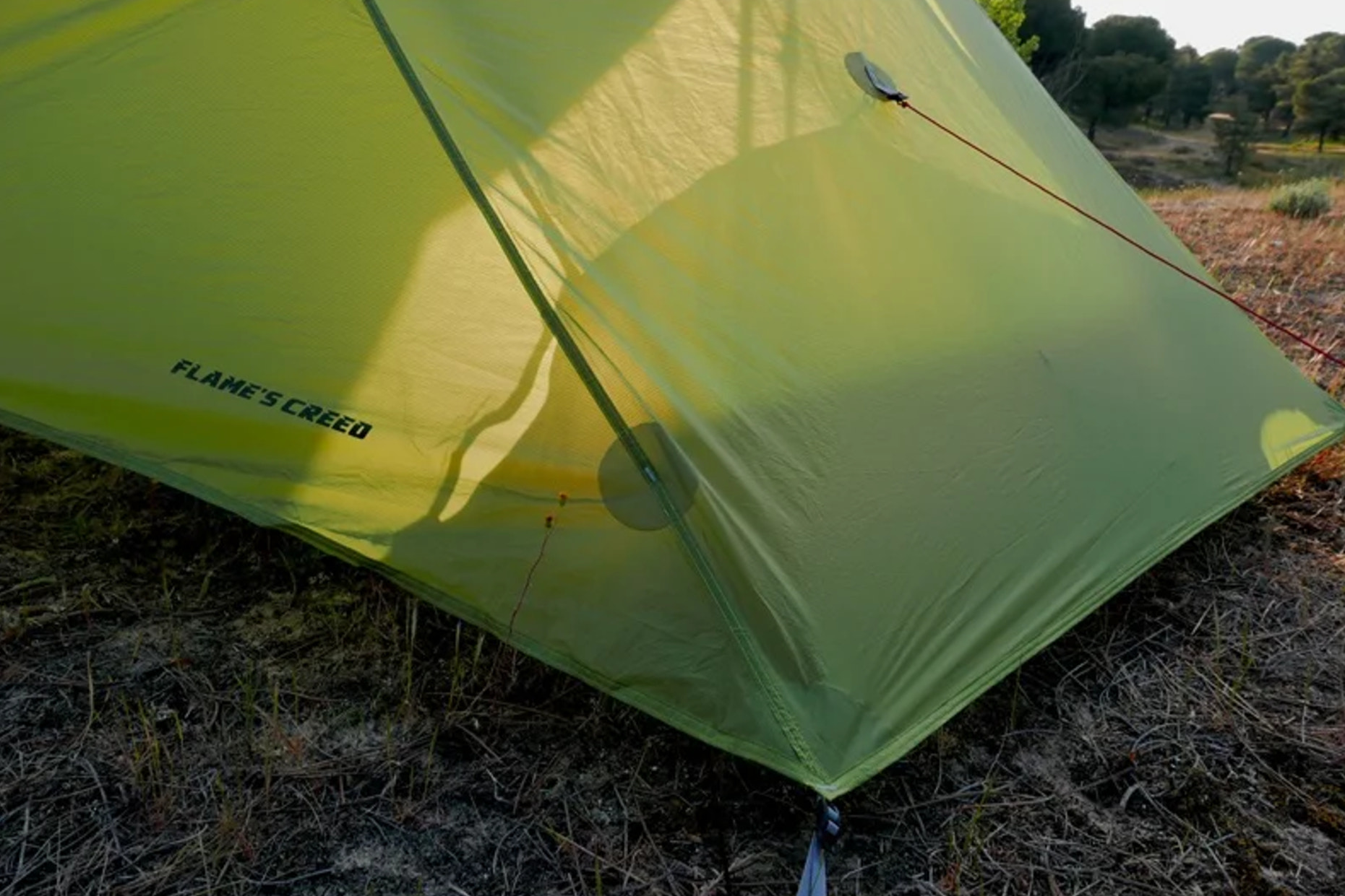 Green tent with 'Flame's Creed' branding in a natural setting