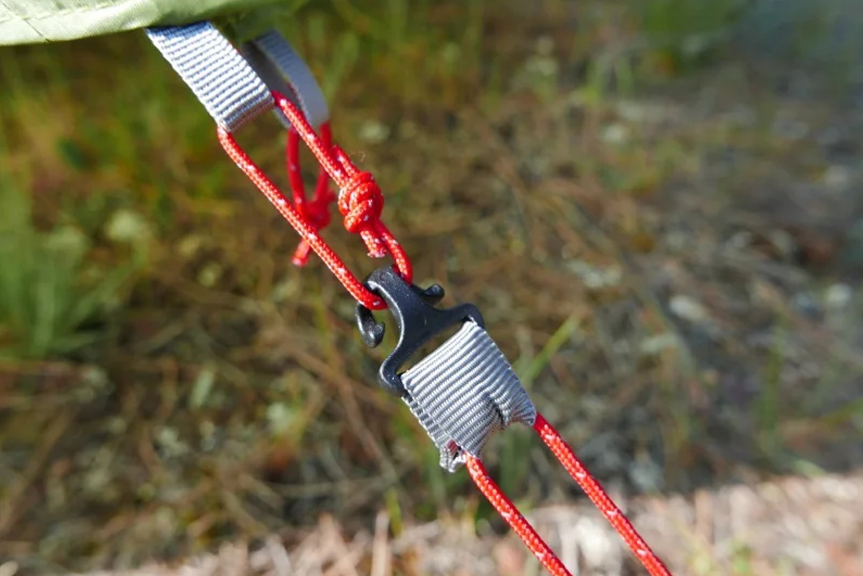 Close-up of a red rope with a clip against a blurred natural background