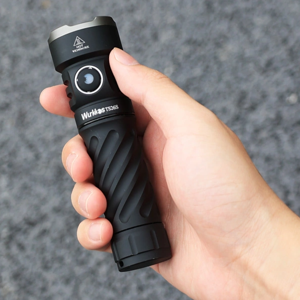 Hand holding a black flashlight with visible branding against a gray background