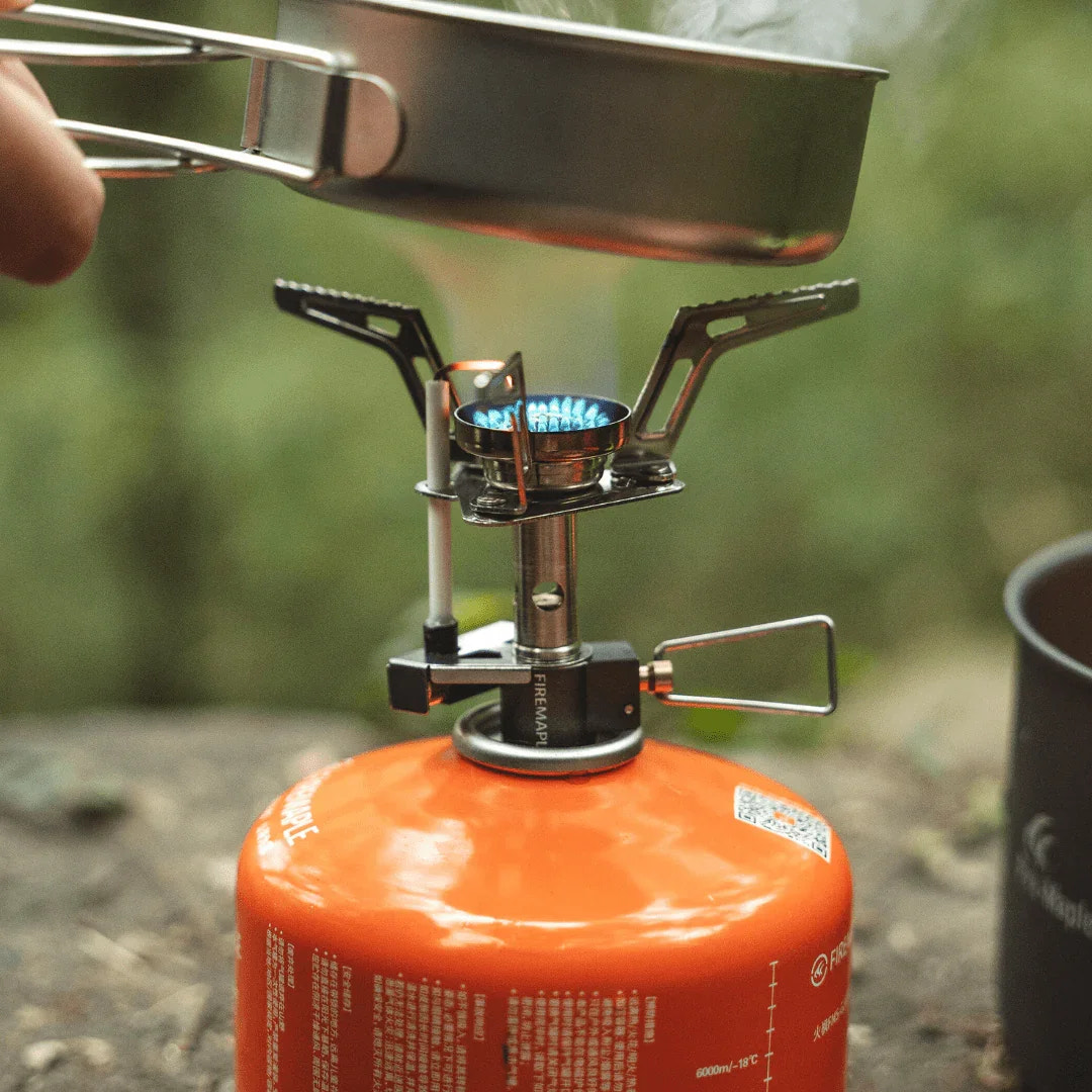 Portable gas stove with a pot on top, set against a natural background