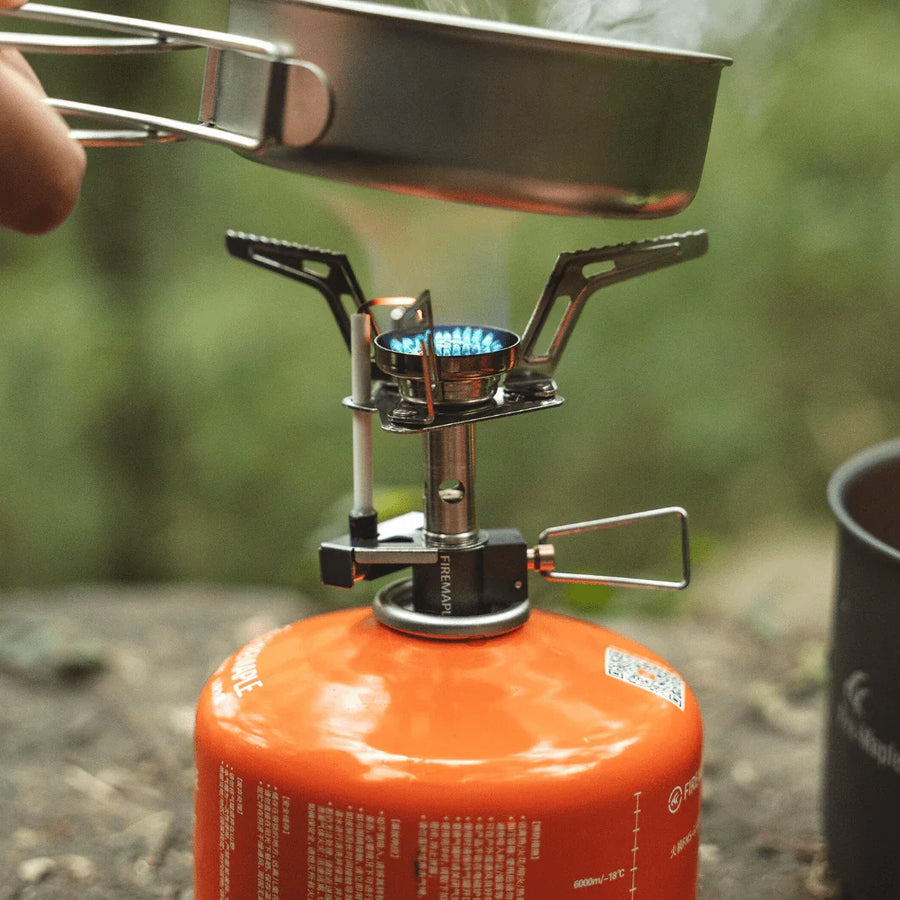 Portable gas stove with a pot on top, set against a natural background