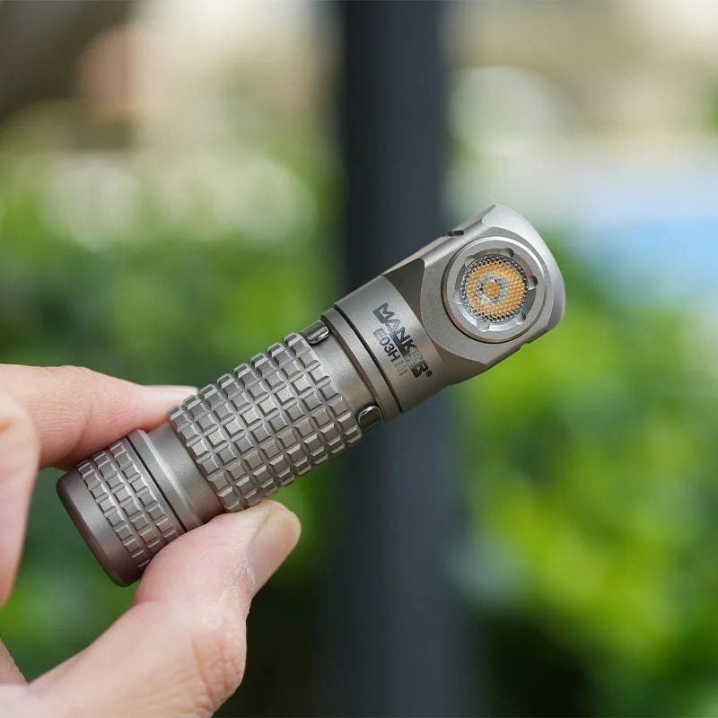 Hand holding a tactical flashlight with a blurred green background