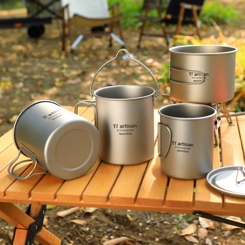 Set of titanium mugs on a wooden table with a camping background