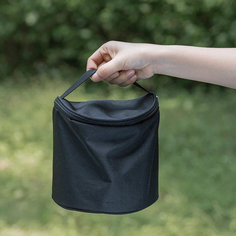 Black reusable bag held by a hand with a blurred green background