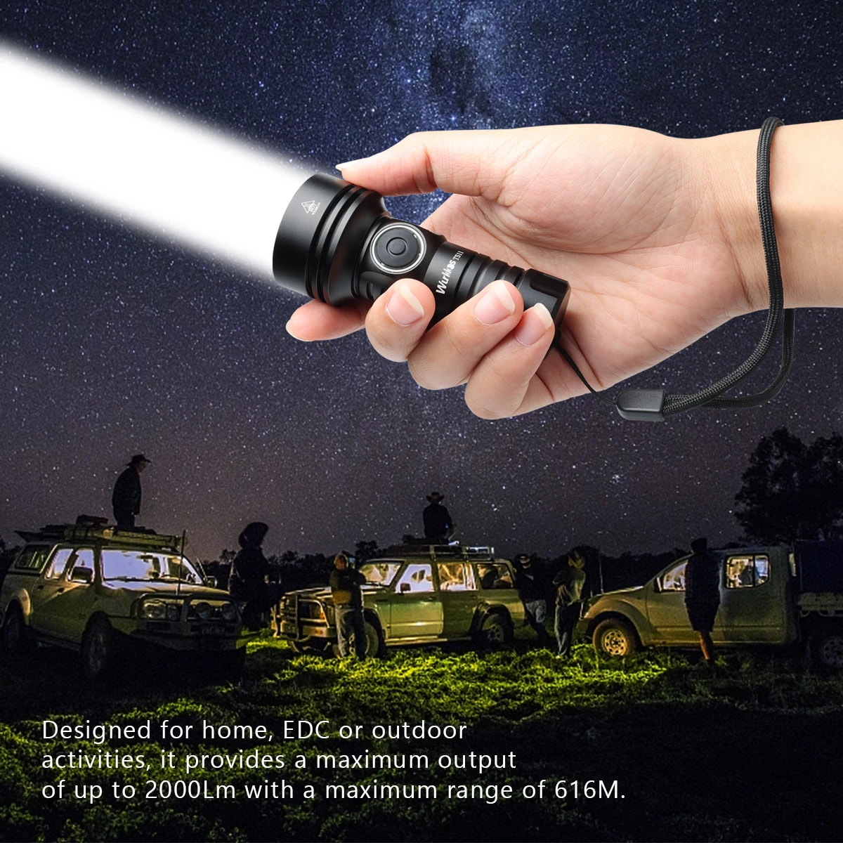 Hand holding a flashlight with a dark sky and people in the background