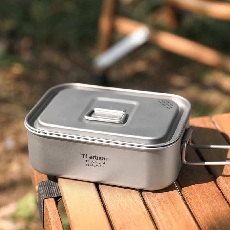 Titanium cooking pot with lid on a wooden surface outdoors