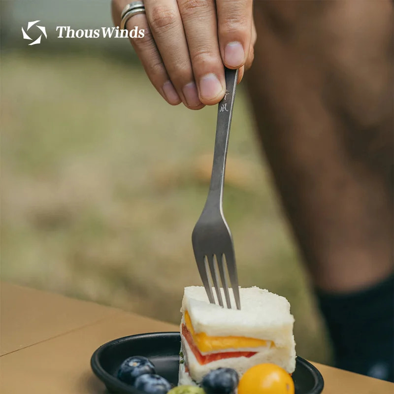 Person holding a fork over a sandwich with a blurred background