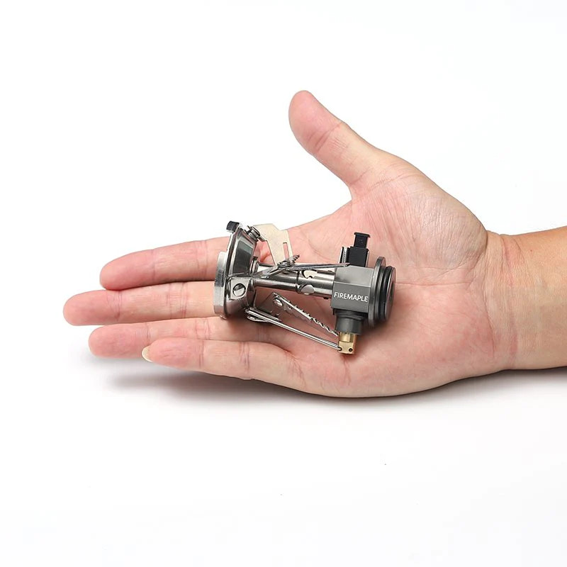 Small camping stove held in a hand on a white background