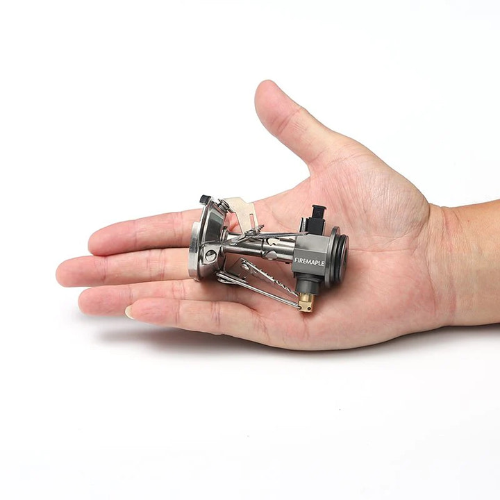 Small camping stove held in a hand on a white background