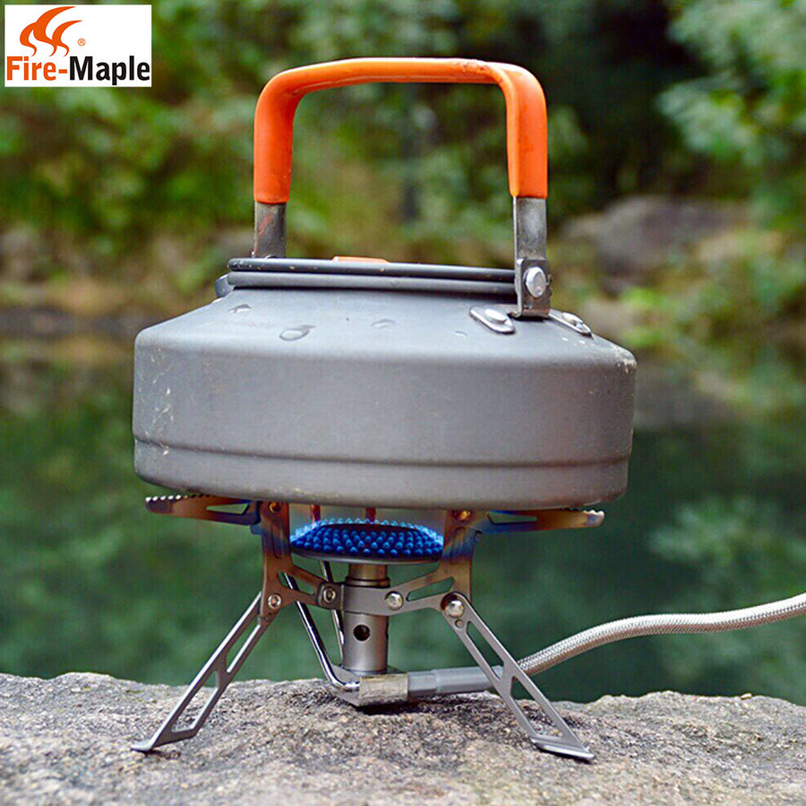 Camping stove with gray pot and orange handle on a rock, Fire-Maple brand visible